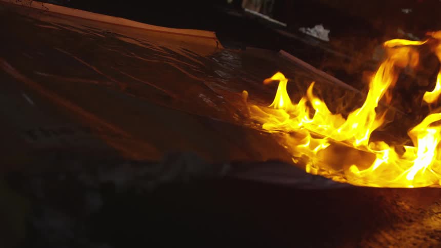 Flames burn over a piece of paper