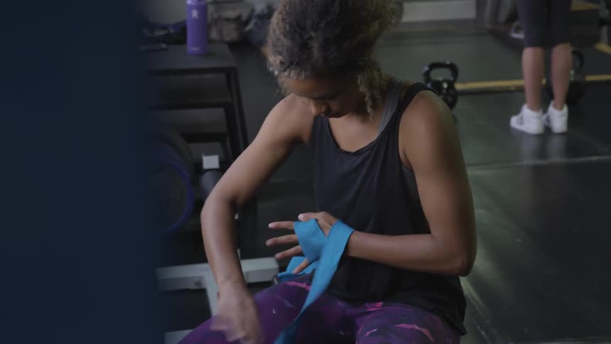 A woman wraps her hand with athletic tape in a gym