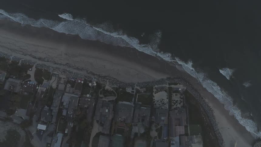 Waves crashing on a beach by houses