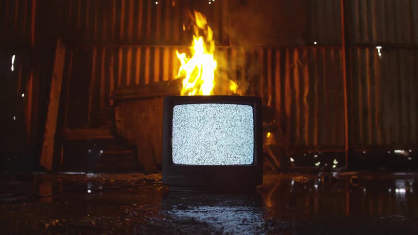 A fire has started behind a television in a room