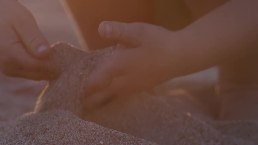 A child uses his hands to scoop up beach sand