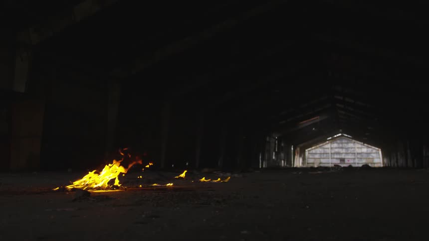 Fire on the ground near a dilapidated building