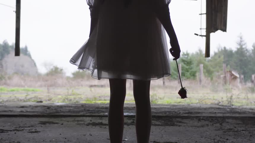 A female stands in a dress holding a flower