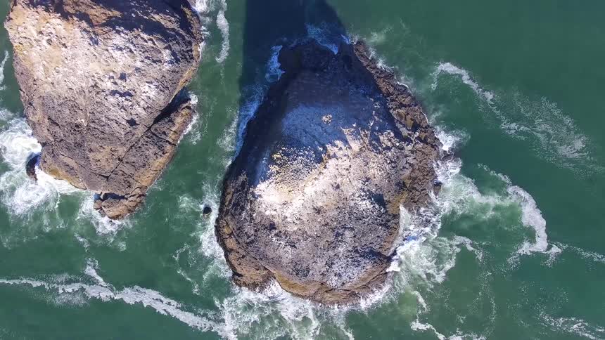 Birds eye view of rocky island in ocean with waves