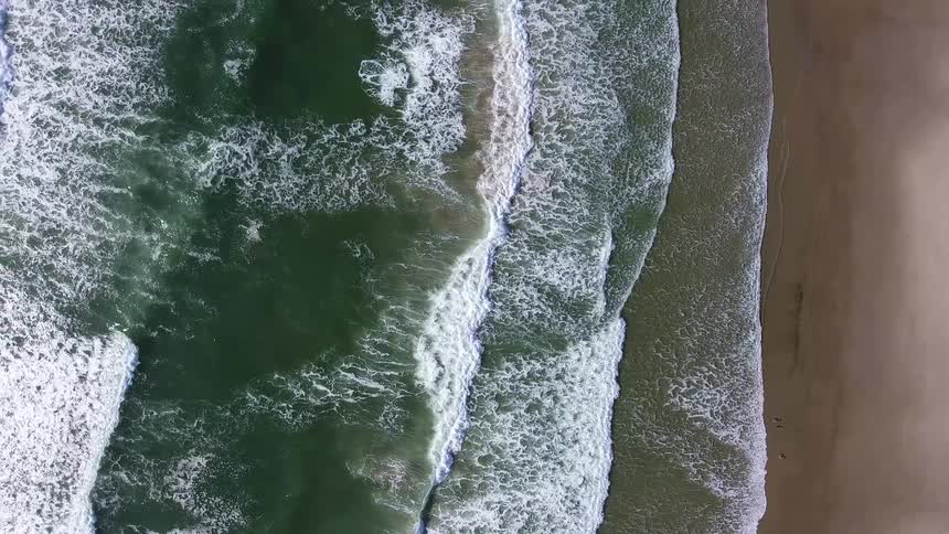 Ocean waves break and splash as they come to a sandy shore