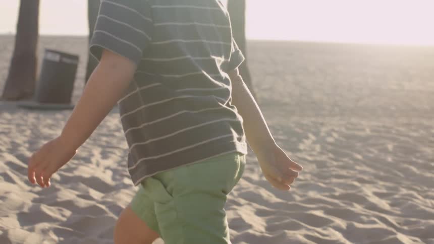 Young boy runs and plays on the beach on a sunny day