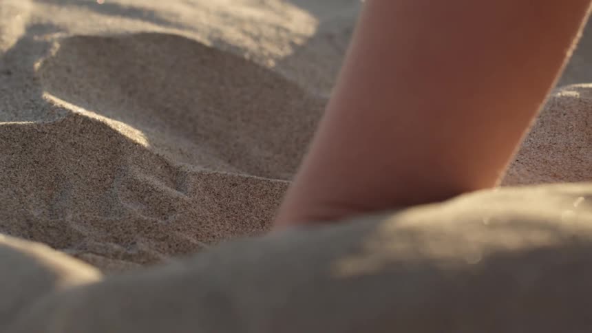 Child puts their hand in the sand and picks it up
