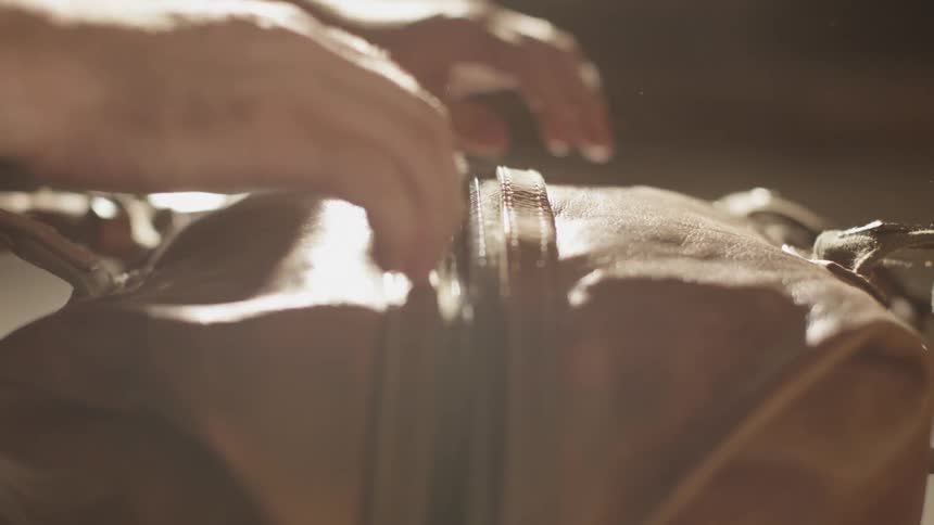 A man unzips a large duffel bag and removes two books