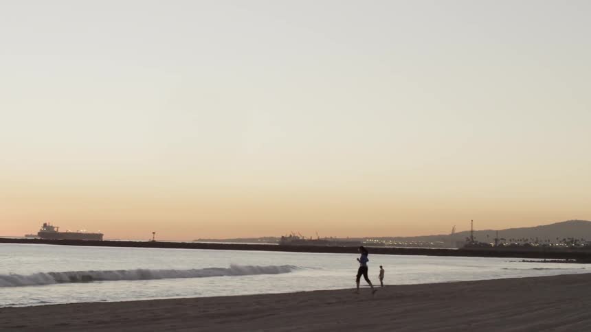 A woman jogging on a beach at sunset