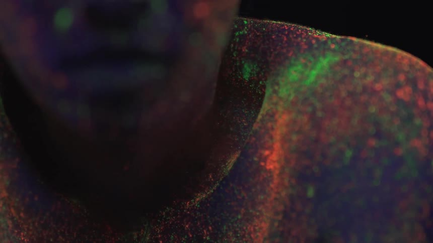 Woman with neon glow in the dark paint stares in a dark room