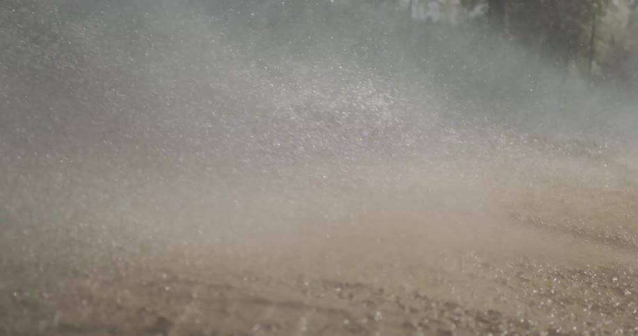 A spray of water pelts a muddy ground