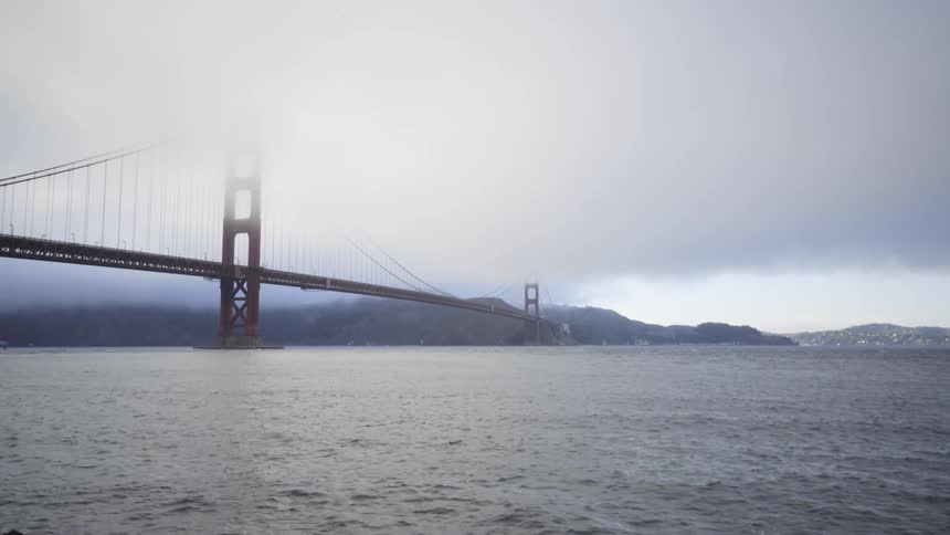 Water ripples beneath a suspension bridge on an overcast day