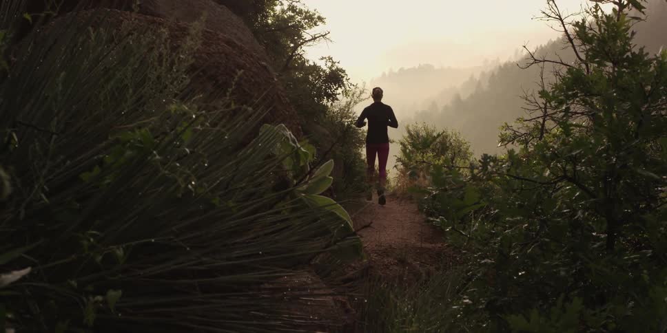 Woman jogs down a dirt path on the cliffside