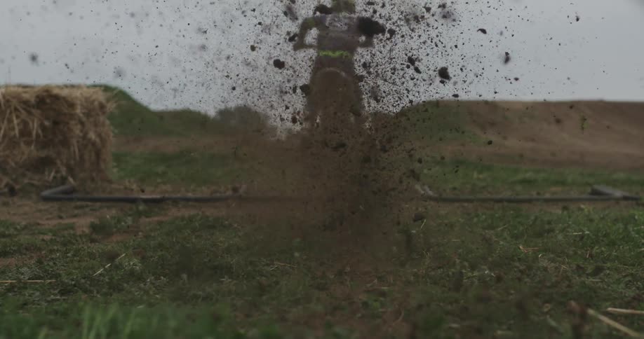 As the start gate is dropped the dirt bike takes off and kicks up dirt