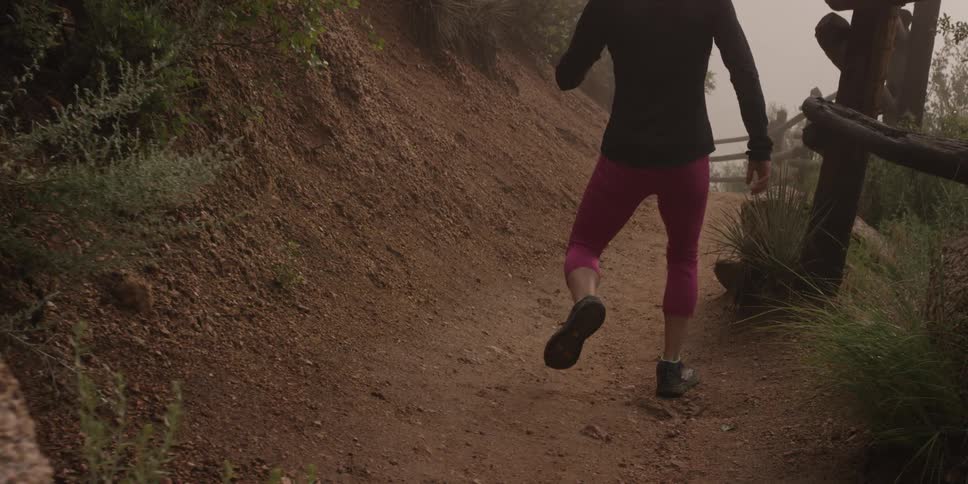 A woman in athletic wear walking along a dirt path