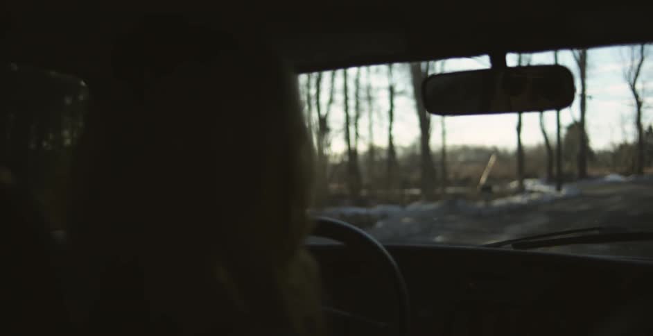 Woman can be seen in the rear view mirror of a car as she drives