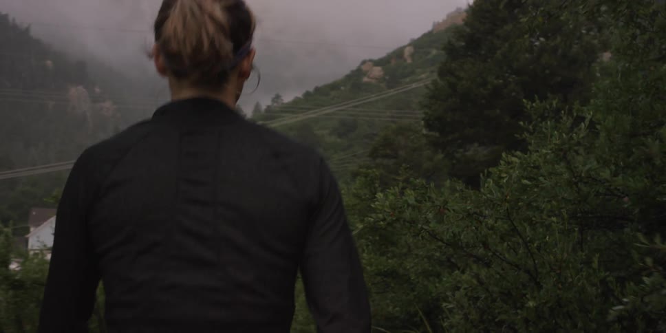 A woman walks along a mountain path on an overcast day