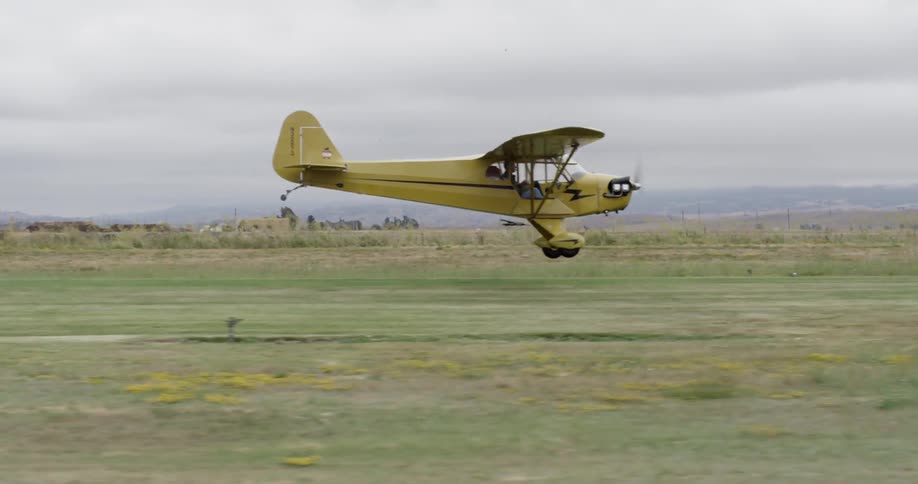 A small crop duster plane takes off in a field on an overcast day