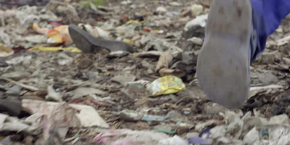 A person walking through rubble and trash