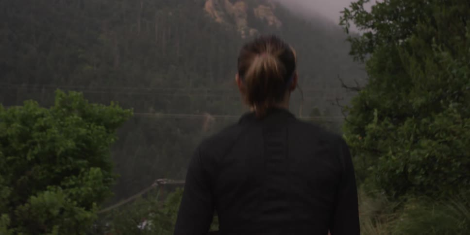 Woman walking by some trees near a cliff on a foggy day