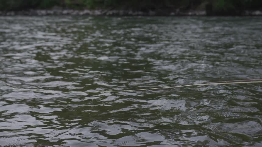 A fishing line resting in the rippling water of the river