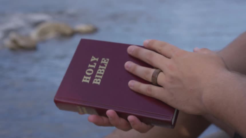 A person is looking at a bible outdoors