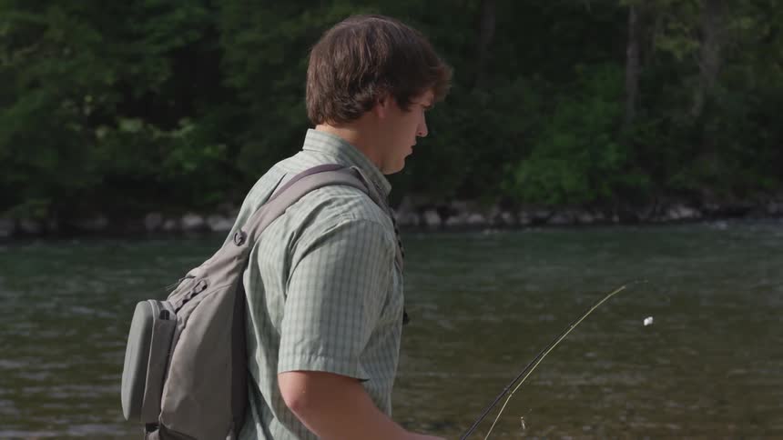 A young man fly fishing on a river