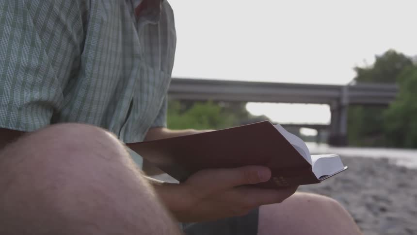 Person sitting in sand reading a book