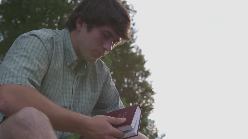 Man sits outside holding holy bible