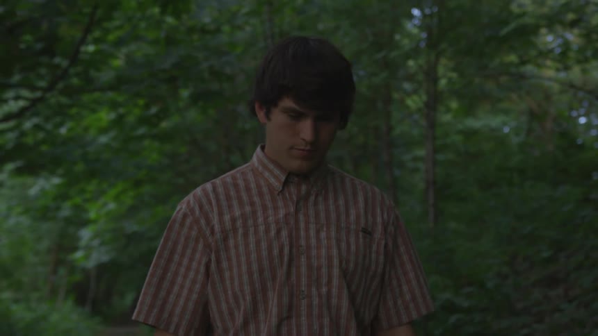 Man wearing striped shirt walks in the forest
