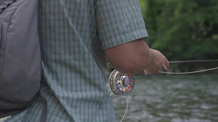 A person is holding a fishing pole in the river