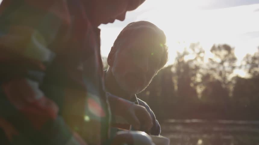 Father and son stick their hands in a bucket