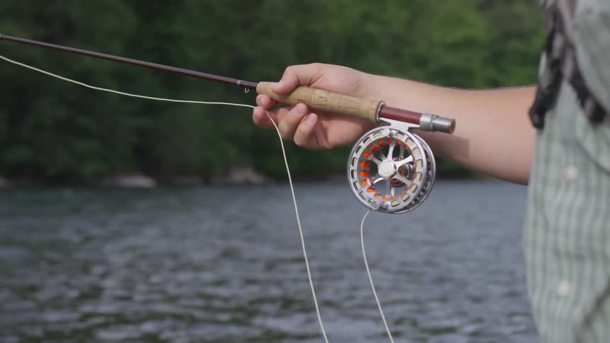 A man is holding a fishing pole outside