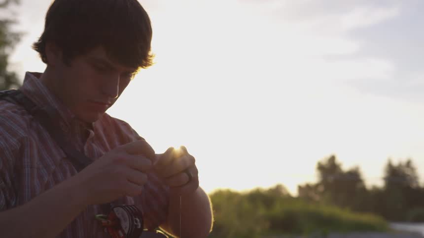 Man works on fishing line outside in early morning