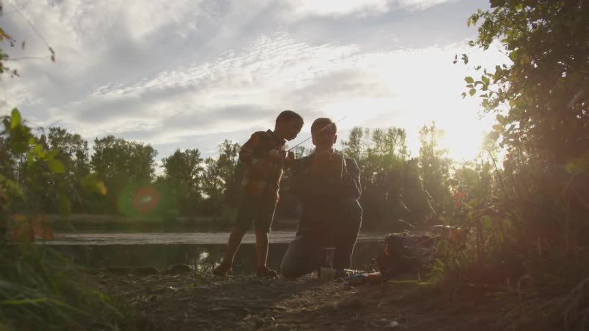 Father and son are outdoors together at sunset