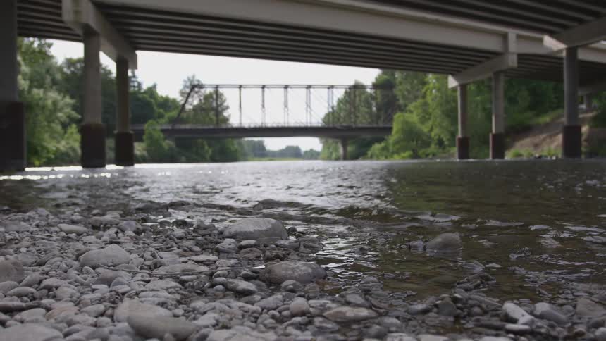 River with rocks flowing underneath a bridge