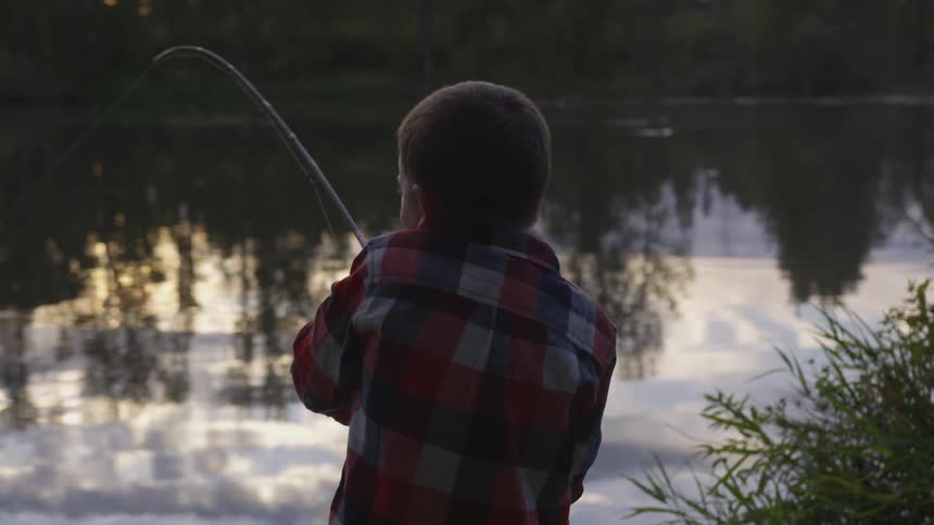 Child along a river catching a fish with a fishing pole