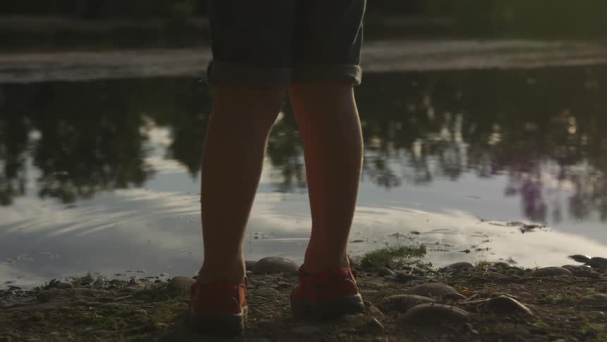 Child stands beside lake with fishing pole