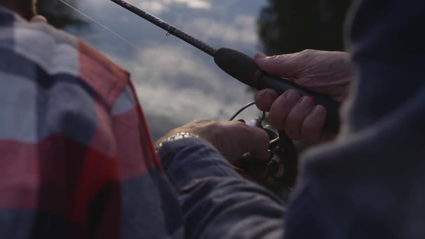 A man turns the reel on his fishing pole as he fishes