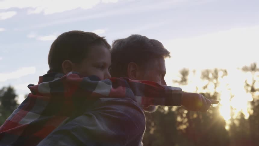 A young boy points a finger while he is being given a piggyback ride by an older man who is likely the boys grandfather