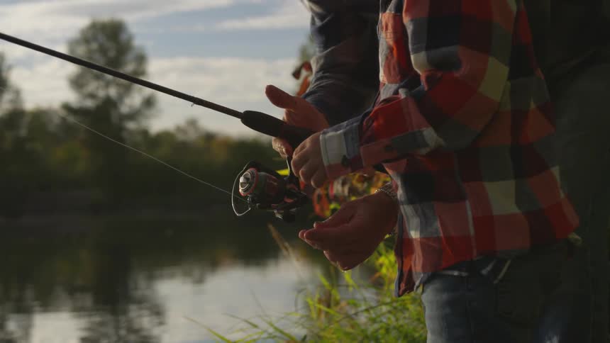 A man standing on the shore reeling in a fishing line