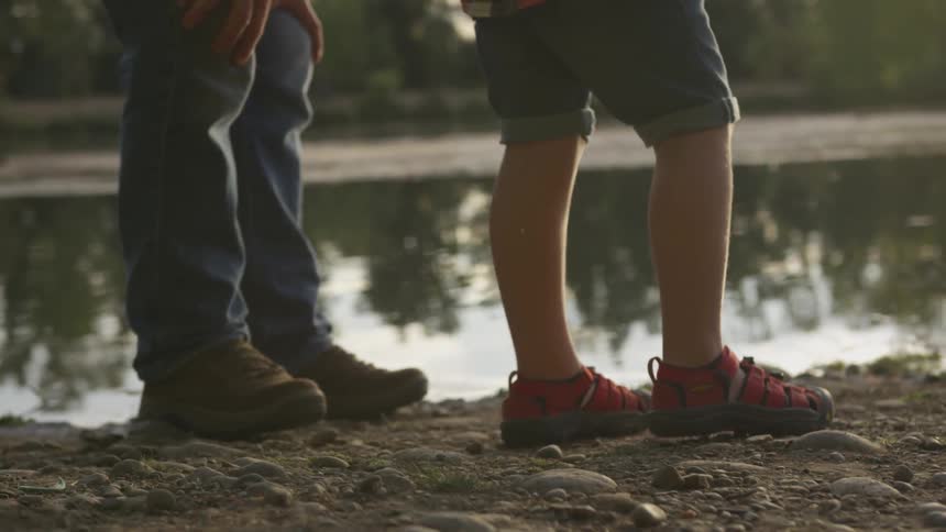 A man and a boy stand near water