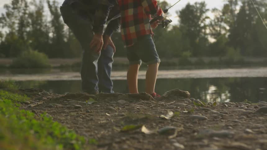 Father and son fish at lake during the day