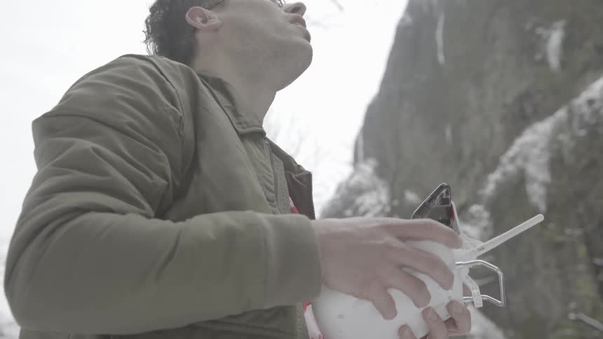 Man wearing glasses holds remote controller on a cold winter's day