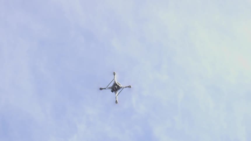 A drone rises up into the cloudy sky