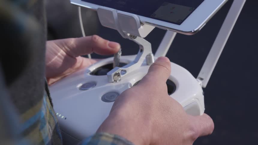 Person uses handheld remote control attached to mobile phone
