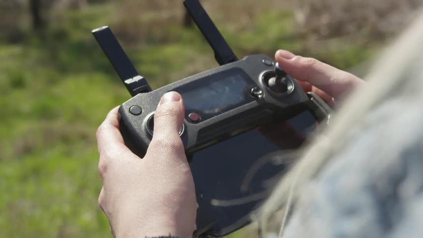 A person using a drone controller in a forested area