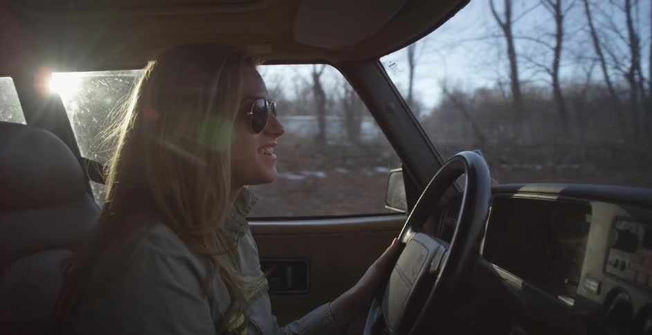 Woman driving a car smiling on a sunny day