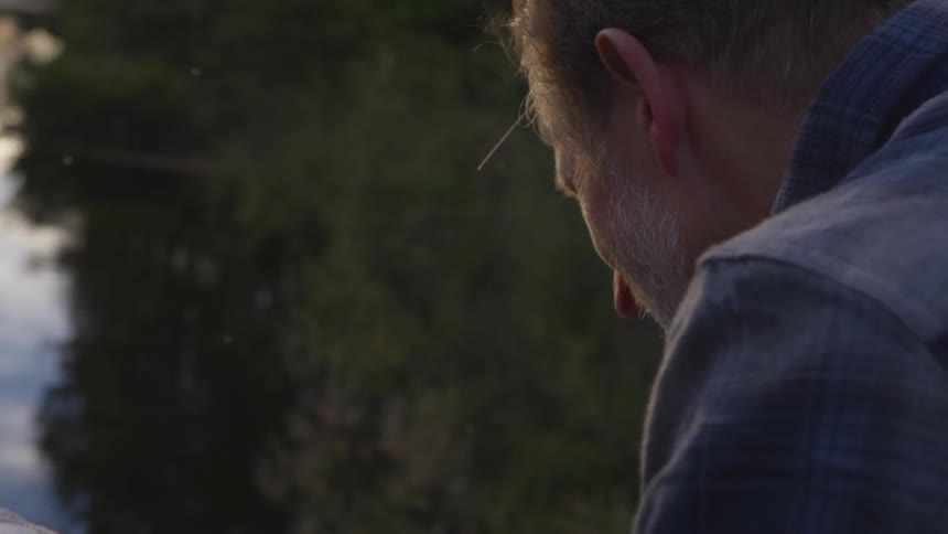 A man sits by the water