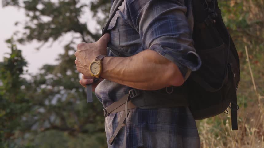 A man wearing a backpack standing in the middle of a forest